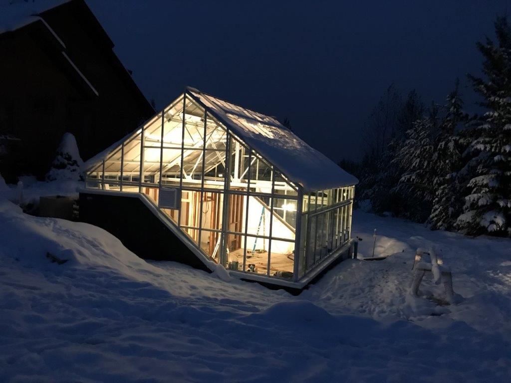 Walipini underground greenhouse at night under blanket of snow